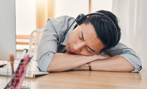 istock Man, burnout and tired at work in call center, communication or customer support job in Shanghai. Asian, worker and crm sleeping in office at customer service, consulting or telemarketing in China 1462768543