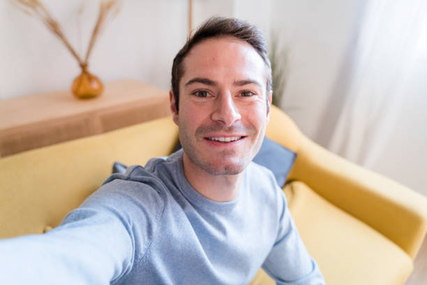 istock Cheerful man doing a selfie on sofa at home 1462770510