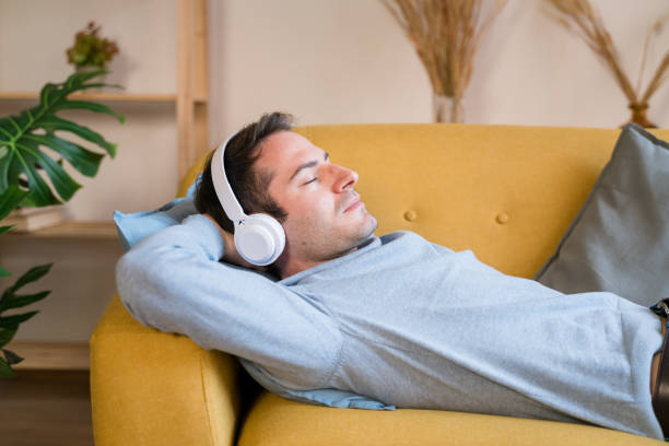 istock Smiling man listening to music on sofa 1462771104
