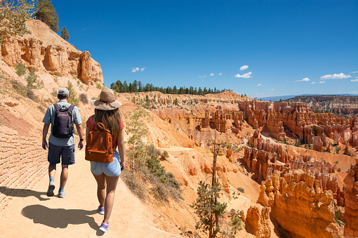 Couple hiking in the red mountains on summer vacation. Friends hiking on  the desert in Utah exploring hoodoos. People on summer hiking trip in the mountains. Bryce Canyon National Park, Utah, USA