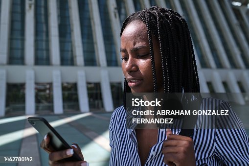 istock Worried african businesswoman using a mobile in the street 1462780142