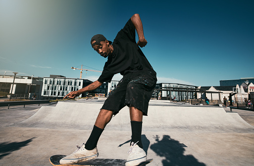 Black man, skater on skateboard and skate trick in a park in  Los Angeles California summer sun for fitness, exercise and fun. Extreme sports athlete, cardio workout and skating competition training