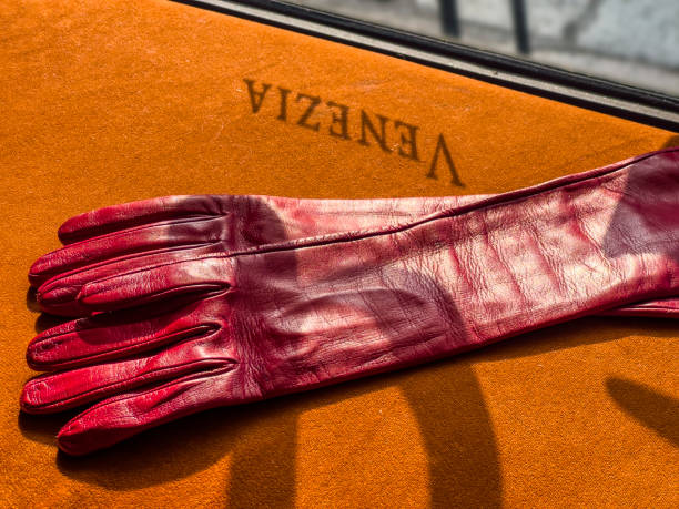 Travel destination Venice, Italy concept. The shadow of letters on a display window at a bar are reflecting upside down on an orange sofa surface. Sunlight falls on red leather lady gloves from a souvenir shop. Poster template background, copy space.