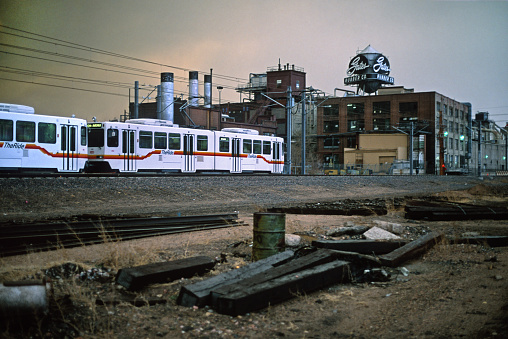 At dusk as rain falls, storm clouds pass over the RTD Light rail station at I-25 and South Broadway with the now demolished Gates Rubber Company water tower and factory in the background in Denver, Colorado on March 21, 2000.