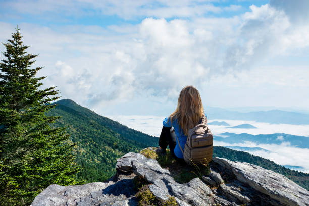 Woman relaxing on top of the mountain on hiking trip. stock photo