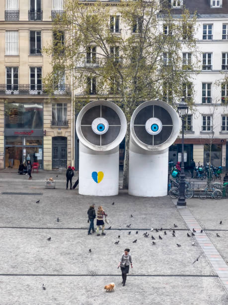 Paris, France, 04/06/2022; White big air ventilation pipes protrude from the floor and bend over a sidewalk. Outside of the Georges Pompidou centre, Paris. Casual people walking around. high angle view.