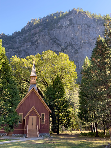 Medium shot of the Yosemite Valley Chapel dwarfed by the granite walls of Yosemite Valley