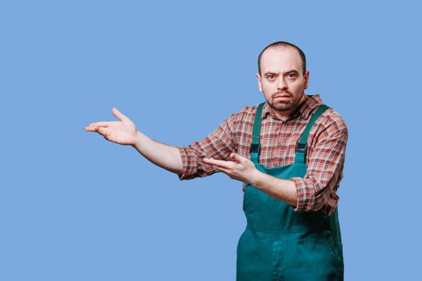 istock With an inquisitive look, the handsome work man dressed in a coverall has his hands spread 1462826404