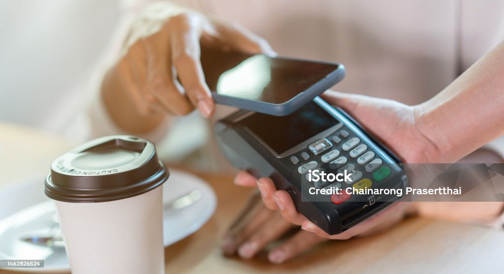 close up contactless payment reader on waitress hand give to customer scan from smartphone to paying bill at table in the cafe fr technology transaction concept Brand Name Mobile Payment Stock Photo