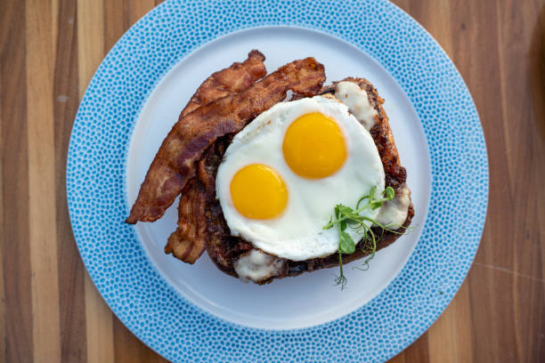 Classic french toast with Nueske bacon and sunny side up eggs on plate setting stock photo