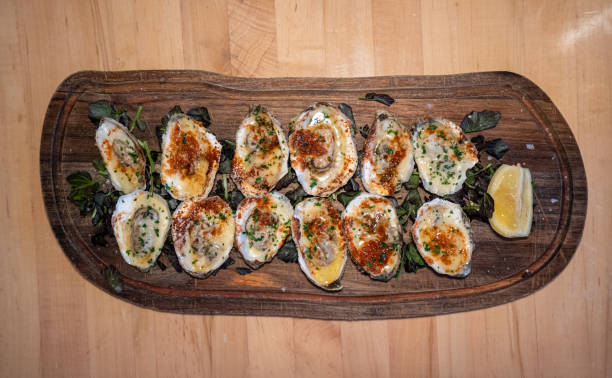 Barbacoa grilled oysters on wooden board with lemon top down stock photo
