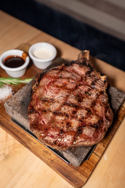 Ribeye steak with bone in on wooden board stock photo