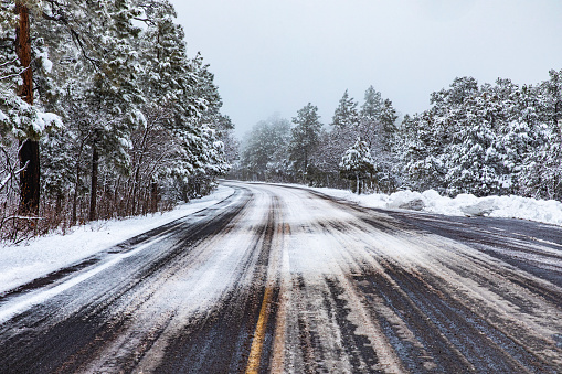 Dangerous country road covered in black ice and snow during winter