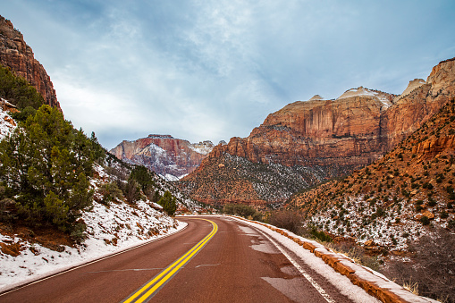 Mountain road through canyon lands covered in ice and snow during winter with beautiful nature scenery.