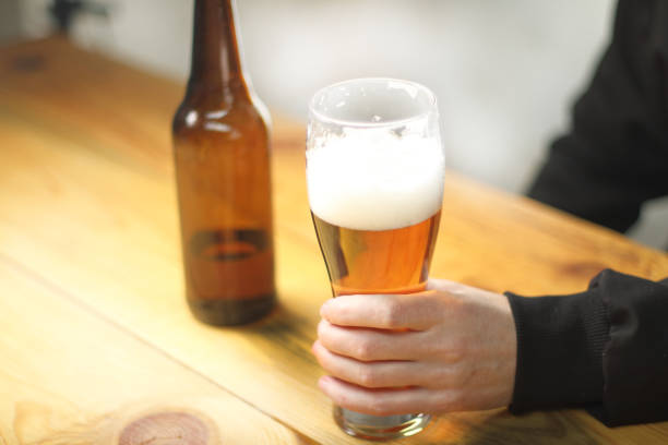 istock person holding a beer mug next to a bottle 1462867732