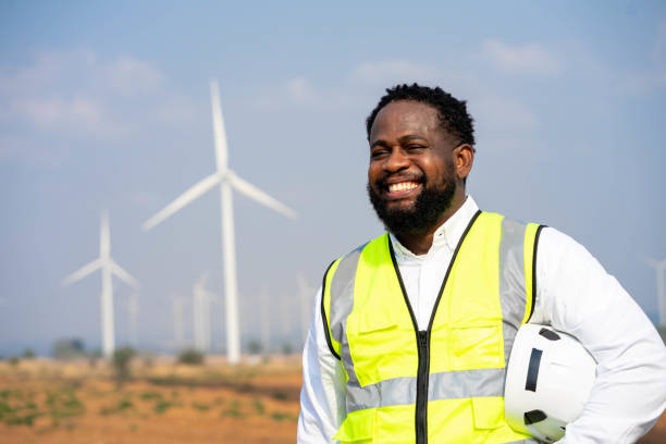 istock African man Engineer in Wind Mill Power Generator Station with white safety hat and wind turbines on background 1462875387