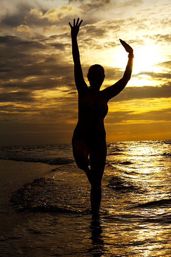 Woman with swimsuit stand exercise in morning and silhouette at beach Hat Wanakon National Park, Prachuap Khiri Khan Province in Thailand is famous for travel and relax
