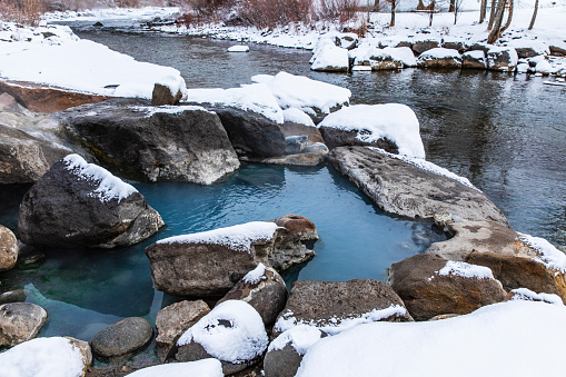 Natural hot water spring mineral pools covered in snow during winter.