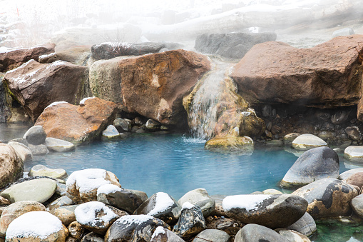 Natural hot water spring mineral pools covered in snow during winter.