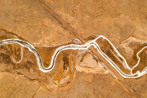 Aerial shot of icy river winding through grassy plain back country in Colorado, USA.