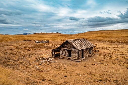 Old abandoned wooden shack in the middle of brown grassy plain, Colorado.