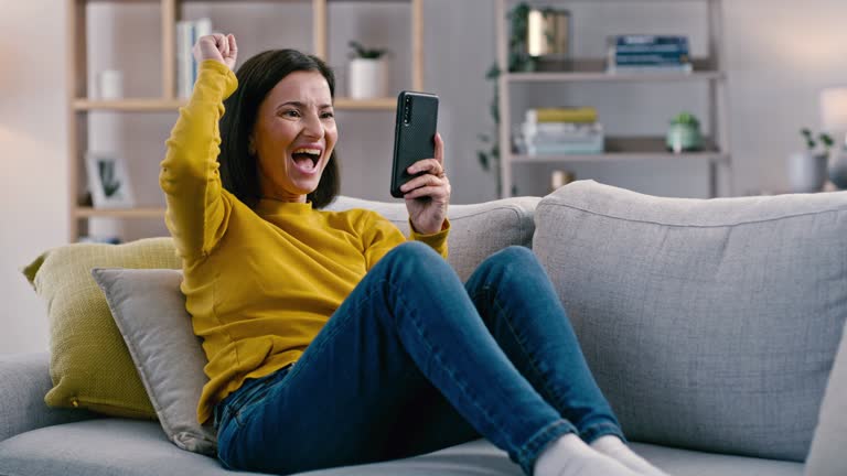 Wow, woman winning and phone on a living room sofa with good news and reward announcement. Happy, excited winner and mature person lounge on a sofa with mobile from win notification and web lottery