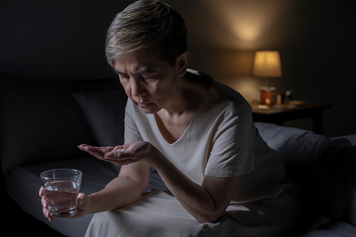 Woman taking medication in bed room
