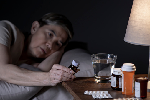 Woman suffering from insomnia taking medication in bed