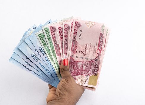 Black Female hand holding the (New) Nigerian currency banknotes , the Naira with a white background