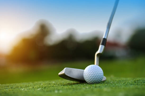 golf clubs and golf balls on a green lawn in a beautiful golf course with morning sunshine. - putten stockfoto's en -beelden