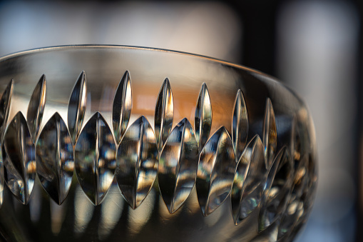 This image shows a macro close-up abstract view of a beautiful hand-cut modern lead crystal bowl, with defocused background.