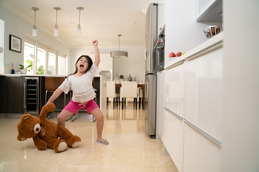 Little girl fighting a teddy bear