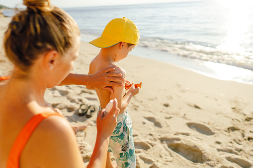 Photo of a mom applying sunscreen lotion on her son's skin