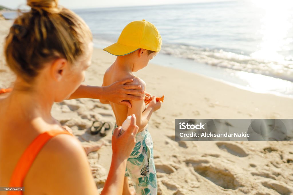 Family Using Sunscreen Applying Sunscreen While At The Beach Stock Photo - Download Image Now ...