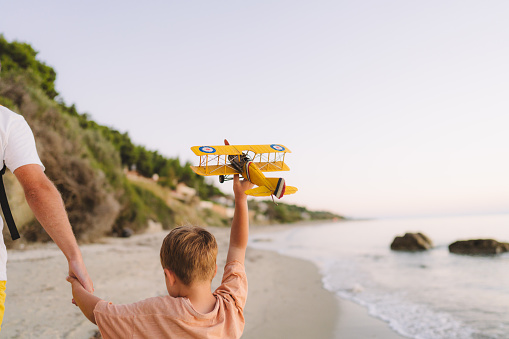 Photo of father and son playing with an airplane toy at the beach