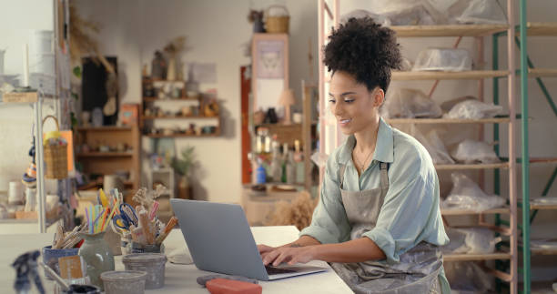 istock Laptop, pottery studio and woman typing ceramic sales website, ecommerce advertising or e commerce service. Artist online shopping, startup retail store and African small business owner in workshop 1462928139
