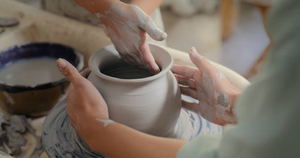 istock Help, hands of woman and child on pottery in workshop classroom, teaching and learning in creative studio. Education, creativity and art, girl in sculpture class with teacher making bowl, pot or vase 1462929420