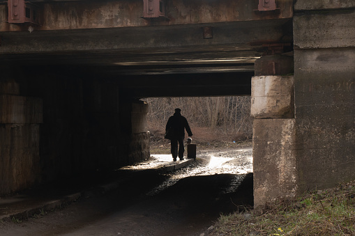 silhouette of a man passing under a railway bridge