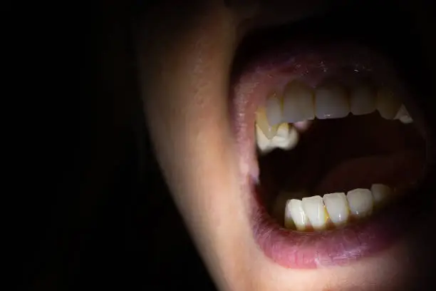 female mouth in the dark illuminated by a lantern