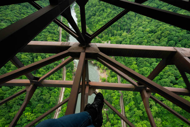 Feet dangling above the New River Gorge from beams on the New Rier Gorge bridge, Fayetteville, West Virginia, USA