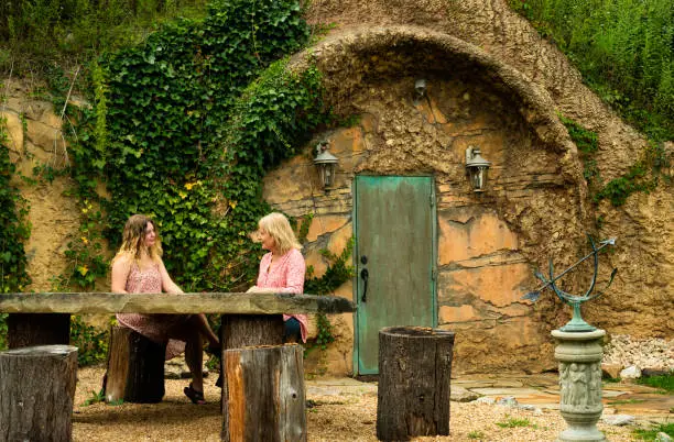 Blond women sit at a rustic table on tree stump stools outside the Pomona Salt Cave and Spa, West Virginia, USA