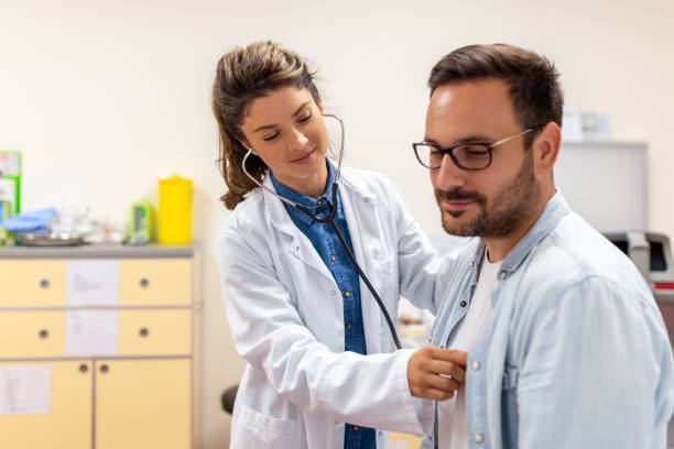 Caring Caucasian female doctor use phonendoscope examine male patient heart rate at consultation in hospital. Woman nurse or GP use stethoscope listen to man heartbeat in clinic. la doctora caucásica que cuida el uso del fonendoscopio examina la frecuencia cardíaca del paciente masculino en la consulta en el hospital. la enfermera o el médico de cabecera usan estetoscopio para escuchar los latidos del corazón del hombre en la c