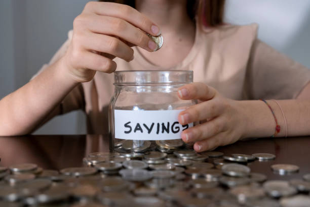 istock Close-up Young girl throws coin into jar 1462941376