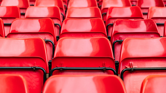 red plastic chair in football, basketball or baseball arena stadium in a row for visitor to visit and enjoy sport match competition for big football match in football stadium