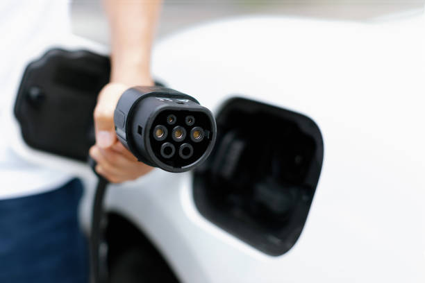 istock Progressive idea of focus hand pointing charging plug at camera, blur background 1462948142