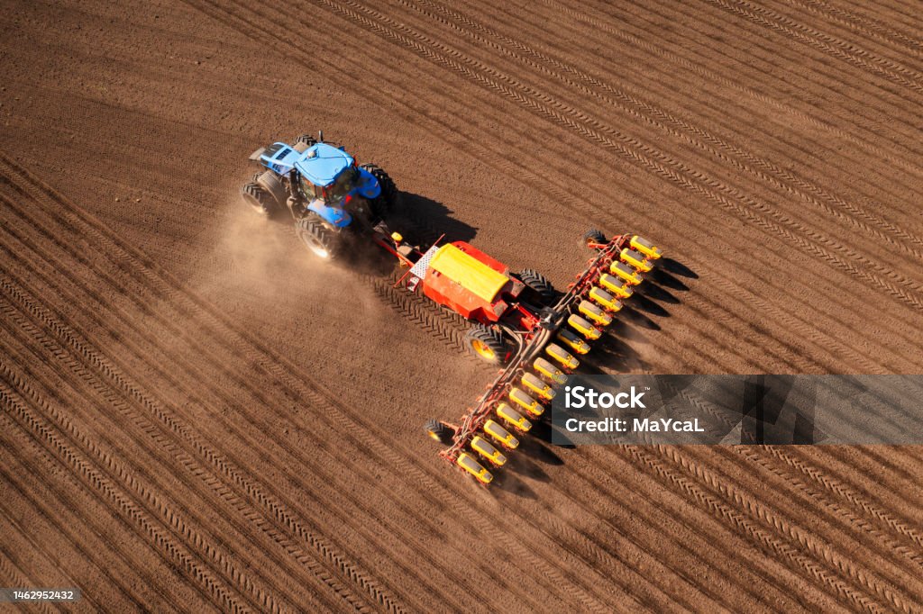 Tractor with seeder on field drone view A tractor with a seeder on the field drone view, the spring season of the sowing campaign. Scenics - Nature Stock Photo