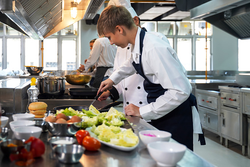 Mature chef using professional oven while preparing food in a restaurant.