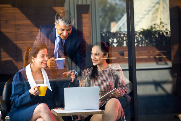 Happy business people drinking coffee and using laptop