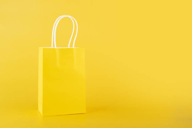 istock shopping bag on yellow background, copy space, monochrome,one color 1462957499
