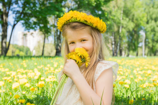 Little girl enjoys the smell of flowers stock photo